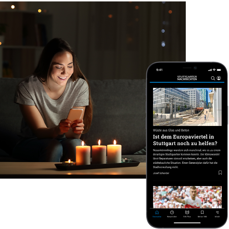 Frau sitzt im Dunkeln vor Kerzen und hält Smartphone in ihren Händen
